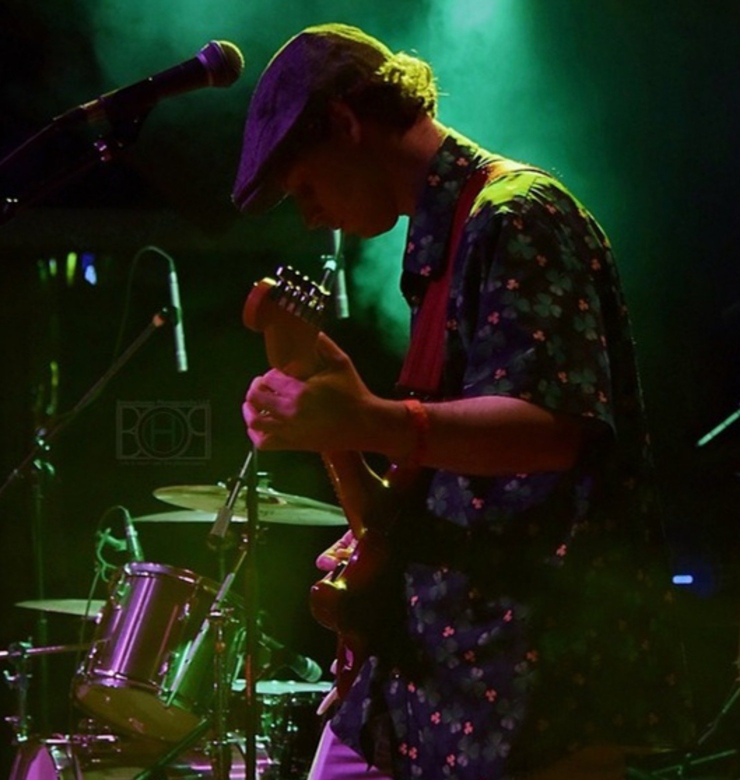 Austin Finnegan playing guitar on stage under green lights