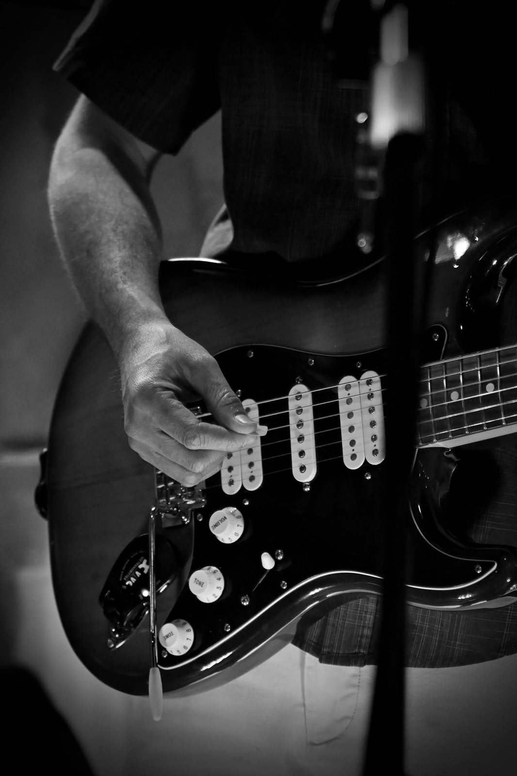 Black and white close-up of Austin Finnegan’s picking hand on his Stratocaster